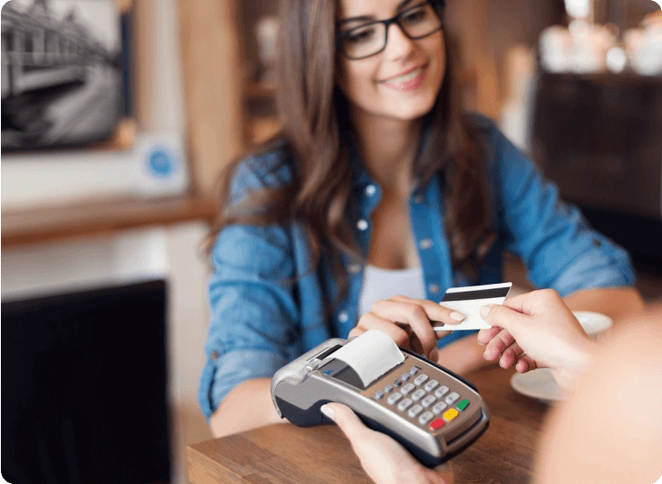 A woman holding her credit card while sitting at the table.