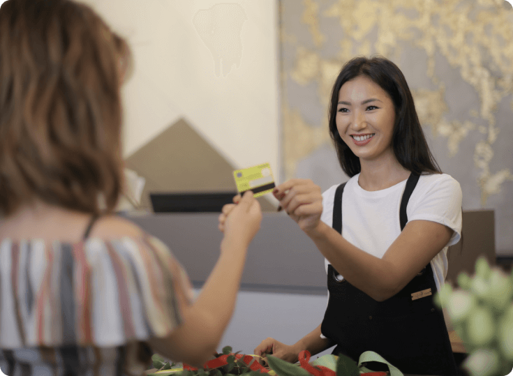 A woman is handing her credit card to another person.