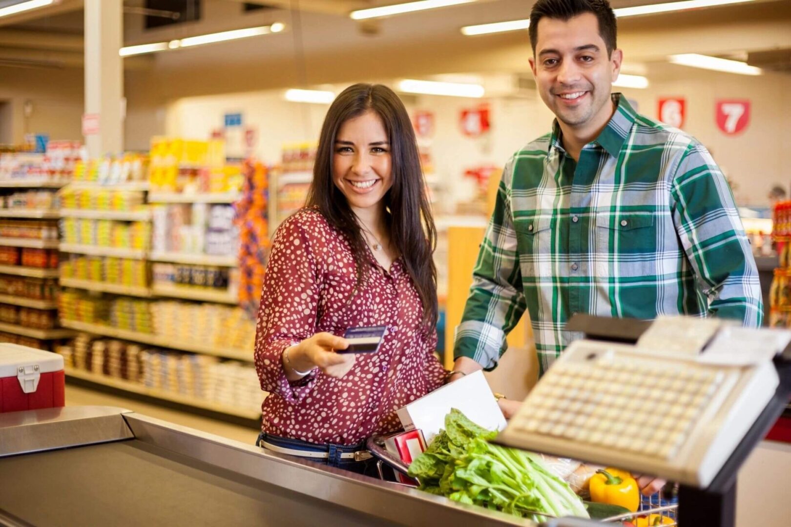 A woman and man behind the counter of a grocery store.